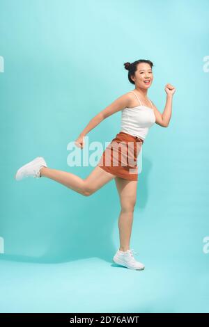 Junge Frau springt auf türkisfarbenem Hintergrund Stockfoto