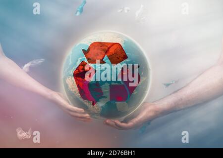 Das Konzept des Umweltschutzes und des Erdtages. Weibliche und männliche Hände halten den Globus des Planeten Erde, umgeben von Müll. Das Recycling-Zeichen. Stockfoto