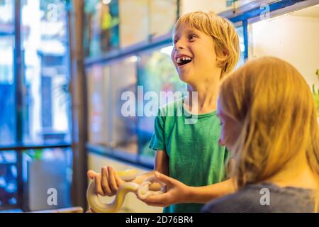 Lächelnder Junge und seine Mutter halten Python in den Händen Stockfoto