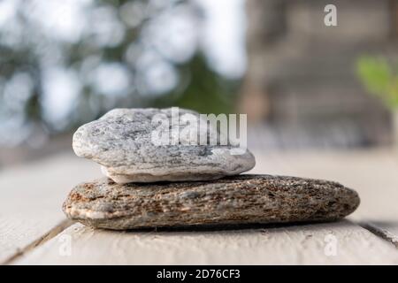Zwei graue Natursteine, der kleine über der großen Nahaufnahme, verwischen den Hintergrund. Stockfoto