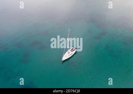 Segeln. Segelboot auf grün blauen Hintergrund Meer vertäut. Sommerferien in Ägäis Griechenland. Luftdrohnenansicht Stockfoto