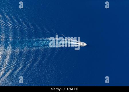 Motorboot, Luxus-Schnellyacht, die auf dem Hintergrund des wellig gekräuselten Meeres navigiert, weiße Wake. Urlaub Aegean Sea Griechenland im Sommer. Luftdrohne Draufsicht Stockfoto