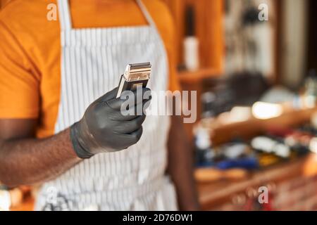 Männlicher Friseur in sterilen Handschuhen mit tragbarem Haarschneider Stockfoto