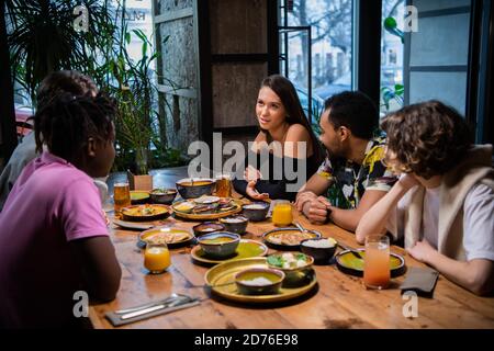 Eine Gruppe von Studenten sitzt am Tisch in einem Café, plaudern, eine schöne Zeit zu haben. Stockfoto