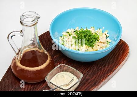 Traditionelle russische kalte Suppe mit Kwass, Okroschka mit Schinken, Gemüse und Sauerrahm auf einem Holzbrett Stockfoto