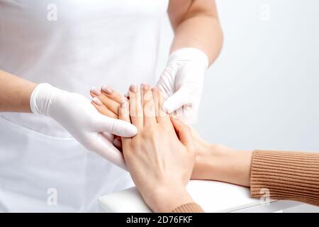 Manikurist trägt Handschuhe dabei Wachs Massage auf weiblichen Händen mit Maniküre im Nagelstudio Stockfoto