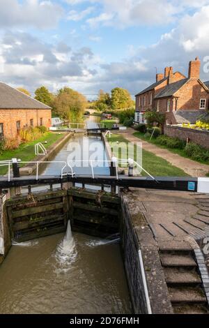 Untere Schleuse am Grand Union Canal bei Braunston in northamptonshire mit schmalen Schleusentoren und historischen Gebäuden auf der Kanalseite. Stockfoto