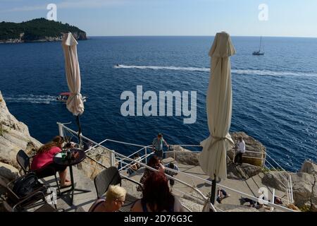 Touristen im Cafe auf den Felsen außerhalb der Stadtmauern von Dubrovnik. Stockfoto