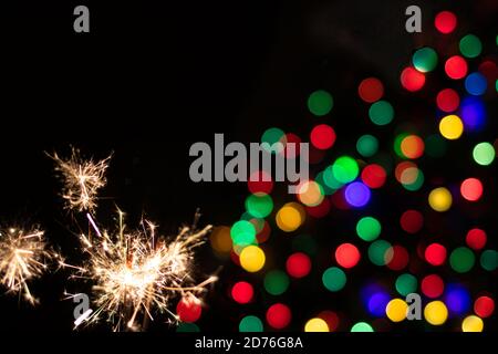 Bengalische Lichter mit goldenen Funkeln auf einem schwarzen festlichen Hintergrund mit mehrfarbigen Seiten. Neujahrsbanner mit den Zahlen 2021 und Sparkler. Stockfoto