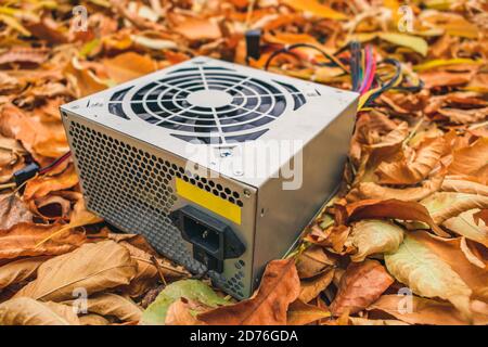 Ein weggeworfenes defektes Computernetzteil liegt im Herbst Laub Stockfoto