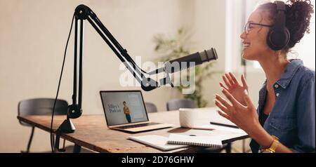 Junge Frau, die einen Podcast aus dem Heimstudio macht. Frau, die einen Podcast für ihren Online-Kanal aufnahm. Stockfoto