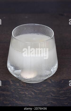 Transparentes Glas auf einer Holzoberfläche mit Vitamin C Brausetablette, Orangengeschmack Stockfoto