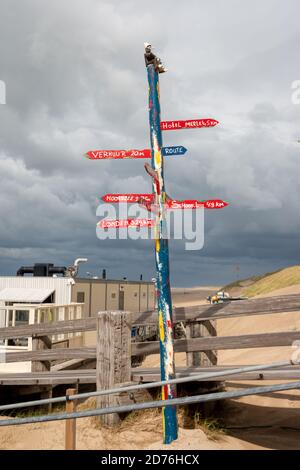 Bunte Straßenschilder auf einem Holzmast am Nordseestrand in der Provinz Noord Holland, Niederlande Stockfoto