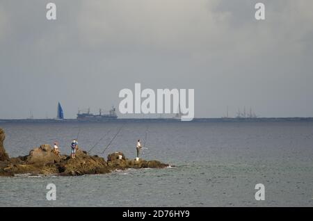 Risco Verde Playa de Arinaga. Aguimes. Gran Canaria. Kanarische Inseln. Spanien. 24. November 2013: Fischer und transatlantisches Rennen im Hintergrund. Stockfoto