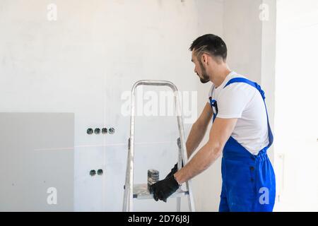 Eine Werkstatt bewegt eine Aluminiumtreppe um den Raum Stockfoto