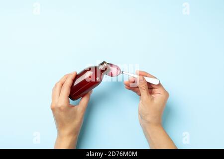 Frau Gießen Sirup in Löffel auf blauem Hintergrund Stockfoto