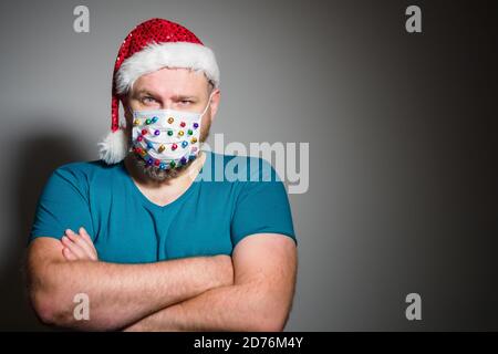 Erwachsene Mann in Weihnachten dekorierte Maske feiern Weihnachtsferien zu Hause, weil Coronavirus. Neue normale, soziale Distanzierung Stockfoto