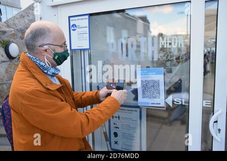 Mann, der die NHS Coronavirus Track and Trace App im Porthmeor Beach Cafe, St Ives, Cornwall, Großbritannien verwendet Okt 2020 MR Stockfoto