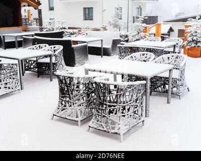 Korbtische und Stühle mit Schnee auf der gestreut stehen Terrasse eines Café im Freien an einem bewölkten verschneiten Tag Stockfoto