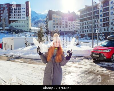 Russland, Sotschi 25.01.2020. Ein Mädchen hält zwei riesige Eiszapfen in den Händen, während es vor dem Hintergrund von Hotels in einem Skigebiet steht Stockfoto