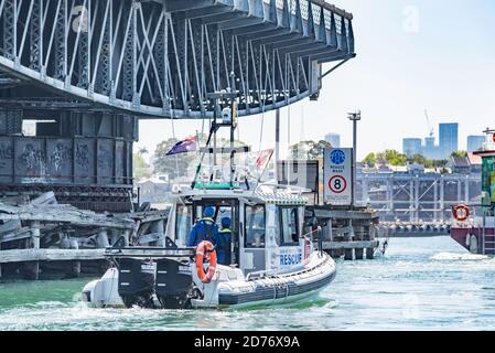 Ein ehrenamtliches maritimes Rettungsboot fährt neben der dauerhaft geöffneten, historischen 1903 Glebe Island Swing Bridge im Sydney Harbour, Australien Stockfoto