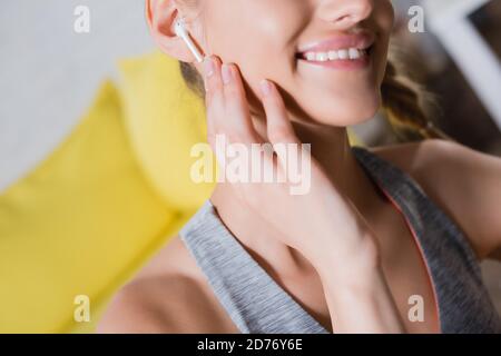 Beschnittene Ansicht einer jungen Frau, die den kabellosen Kopfhörer berührt Stockfoto