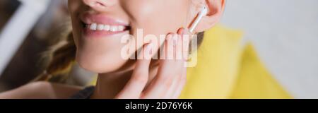 Panoramaaufnahme einer jungen Frau, die den kabellosen Kopfhörer berührt Stockfoto