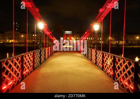 Glasgow, Schottland, Großbritannien... Brücken über den Fluss Clyde bei Nacht. Die South Portland Street Suspension Bridge ist eine Hängebrücke für Fußgänger, die den Fluss Clyde überqueren. Zwischen 1851 und 1853 erbaut, ist es etwa 4 Meter breit und 127 Meter lang und ersetzt die alte Holzbrücke. Es ist eine schöne Möglichkeit, über den Fluss vom südlichen Ende des Stadtzentrums von Glasgow zur Südseite Carlton mit seinem gepflasterten Steinpflaster und georgianischen Reihenhäusern zu gelangen. Stockfoto