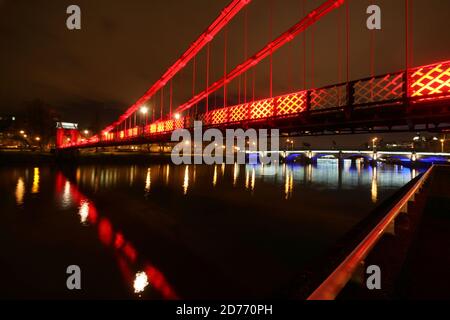 Glasgow, Schottland, Großbritannien... Brücken über den Fluss Clyde bei Nacht. Die South Portland Street Suspension Bridge ist eine Hängebrücke für Fußgänger, die den Fluss Clyde überqueren. Zwischen 1851 und 1853 erbaut, ist es etwa 4 Meter breit und 127 Meter lang und ersetzt die alte Holzbrücke. Es ist eine schöne Möglichkeit, über den Fluss vom südlichen Ende des Stadtzentrums von Glasgow zur Südseite Carlton mit seinem gepflasterten Steinpflaster und georgianischen Reihenhäusern zu gelangen. Stockfoto