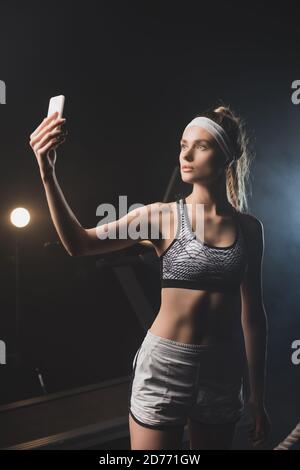 Vorderansicht der Sportlerin beim Selfie im Fitnessstudio Stockfoto