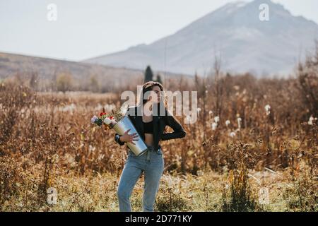 Frau hält einen hohen Eisenkeimer mit Blumen in der Open Air in der Natur Stockfoto