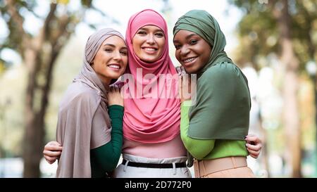 Drei Muslimische Frauen In Hijab Posieren Umarmung Im Freien, Panorama Stockfoto
