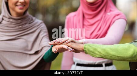 Vereinigte Muslimische Frauen In Hijab Hände Halten Im Freien Stehend, Abgeschnitten Stockfoto