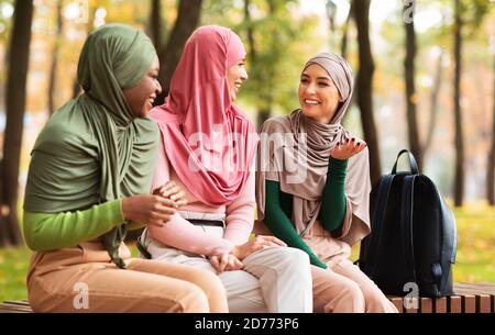 Drei Muslimische Arabische Frauen Sprechen Auf Der Bank Im Park Sitzen Stockfoto