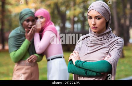 Schlechte Freunde Sprechen Über Unglückliche Muslimische Frau Allein Stehend Im Freien Stockfoto