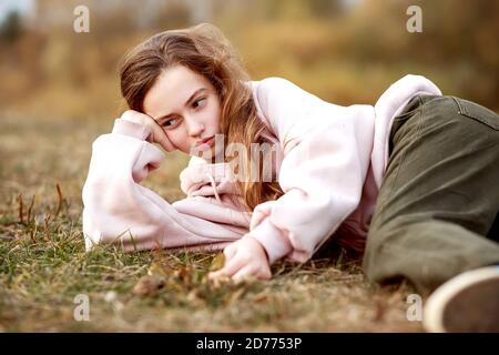 Portrait eines Teenagers in lässiger Kleidung auf dem Gras liegend. Stockfoto