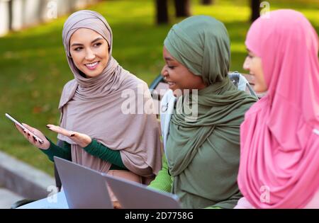 Muslim Lady Empfiehlt Smartphone Mobile Anwendung Für Freunde Sitzen Im Freien Stockfoto