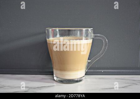 Eine Tasse aromatischen Kaffee mit Milch in einem transparenten becher Stockfoto