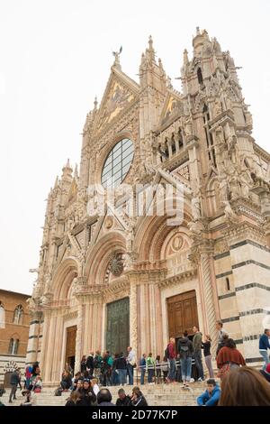 SIENA, ITALIEN - 22. APRIL 2019: Berühmter Dom von Siena mit vielen Touristen vor der Tür Stockfoto