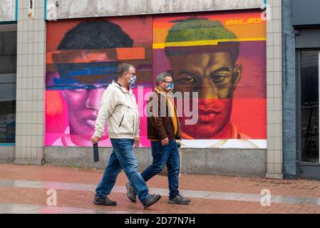 High Street, Southend on Sea, Essex, Großbritannien. Oktober 2020. Um die Feierlichkeiten zum Fest der Schwarzen Leben in Southend, die am 24. Oktober stattfinden, zu fördern, wurde ein Wandgemälde mit Straßenkunst auf den Wall eines geschlossenen Ladens in der High Street in der Stadt gemalt. Das Bild des Fußballers Marcus Rashford MBE ist von Scotty Brave von Bravearts. Die Feier ist Teil des Black History Month. Rashford, der für Manchester Utd und England spielt, hat sich dafür eingesetzt, die Kindernahrungsarmut mit kostenlosen Schulmahlzeiten während der Ferien zu bekämpfen. Passanten mit COVID 19 Gesichtsmasken Stockfoto