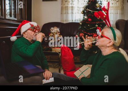 Seniorenpaar zu Hause mit einer Weihnachtsfeier auf einem Videoanruf Stockfoto