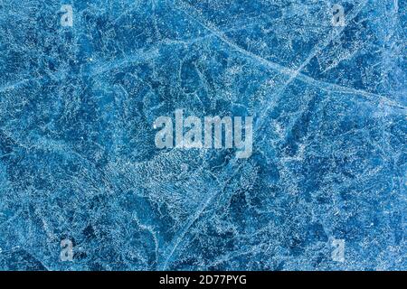 Einzigartige Hintergrundstruktur von Eis. Wintermuster auf dem blauen Eis des Sees. Risse und Luftblasen. Horizontal. Stockfoto