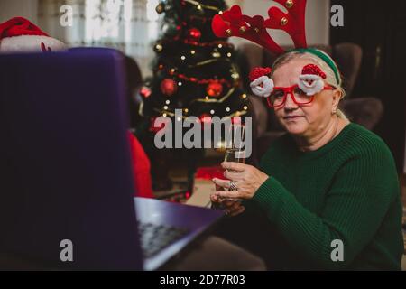Ältere Frau zu Hause mit einer Weihnachtsfeier auf einem Videoanruf Stockfoto