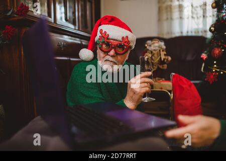 Senior Mann zu Hause mit einer Weihnachtsfeier auf einem Videoanruf Stockfoto