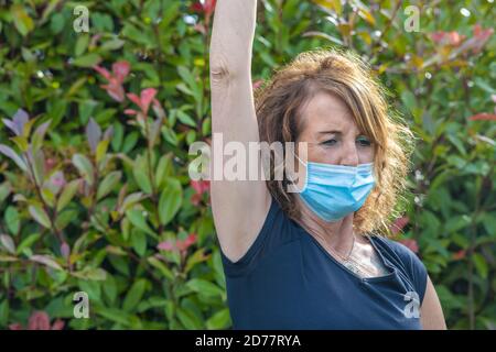 Frau trägt Heide Maske mit Heimfitness im Freien in covid Pandemie. Stockfoto