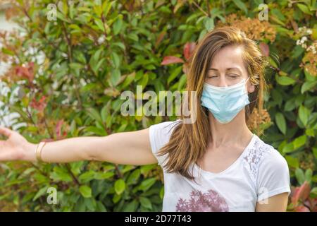 Junge Frau trägt Heide Maske mit Heimfitness im Freien in covid Pandemie. Stockfoto