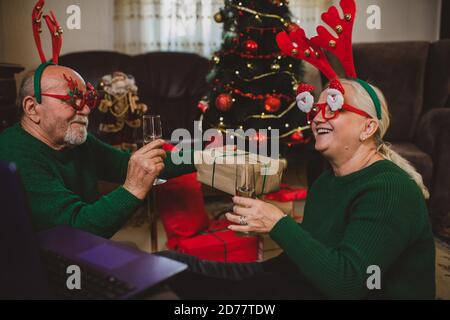 Seniorenpaar zu Hause mit einer Weihnachtsfeier auf einem Videoanruf Stockfoto