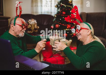 Seniorenpaar zu Hause mit einer Weihnachtsfeier auf einem Videoanruf Stockfoto