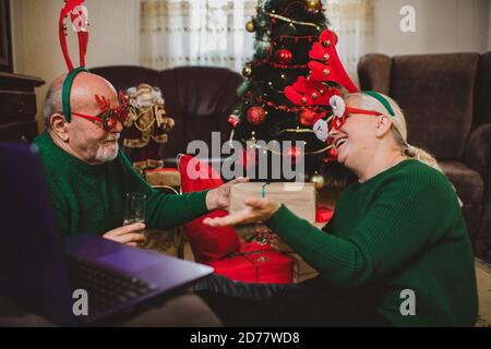Seniorenpaar zu Hause mit einer Weihnachtsfeier auf einem Videoanruf Stockfoto