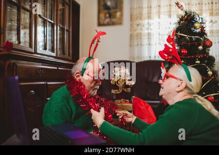 Seniorenpaar zu Hause mit einer Weihnachtsfeier auf einem Videoanruf Stockfoto